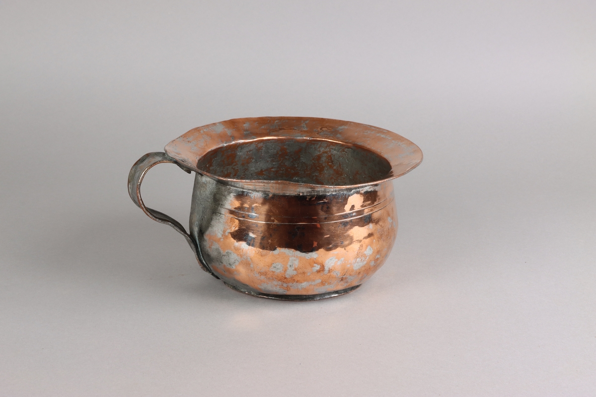Copper chamber pot, plain circle form with flat base, angled rim above domed base with s-scroll handle. The pot shows traces of tin lining in the pot, on the handle and on the sides.