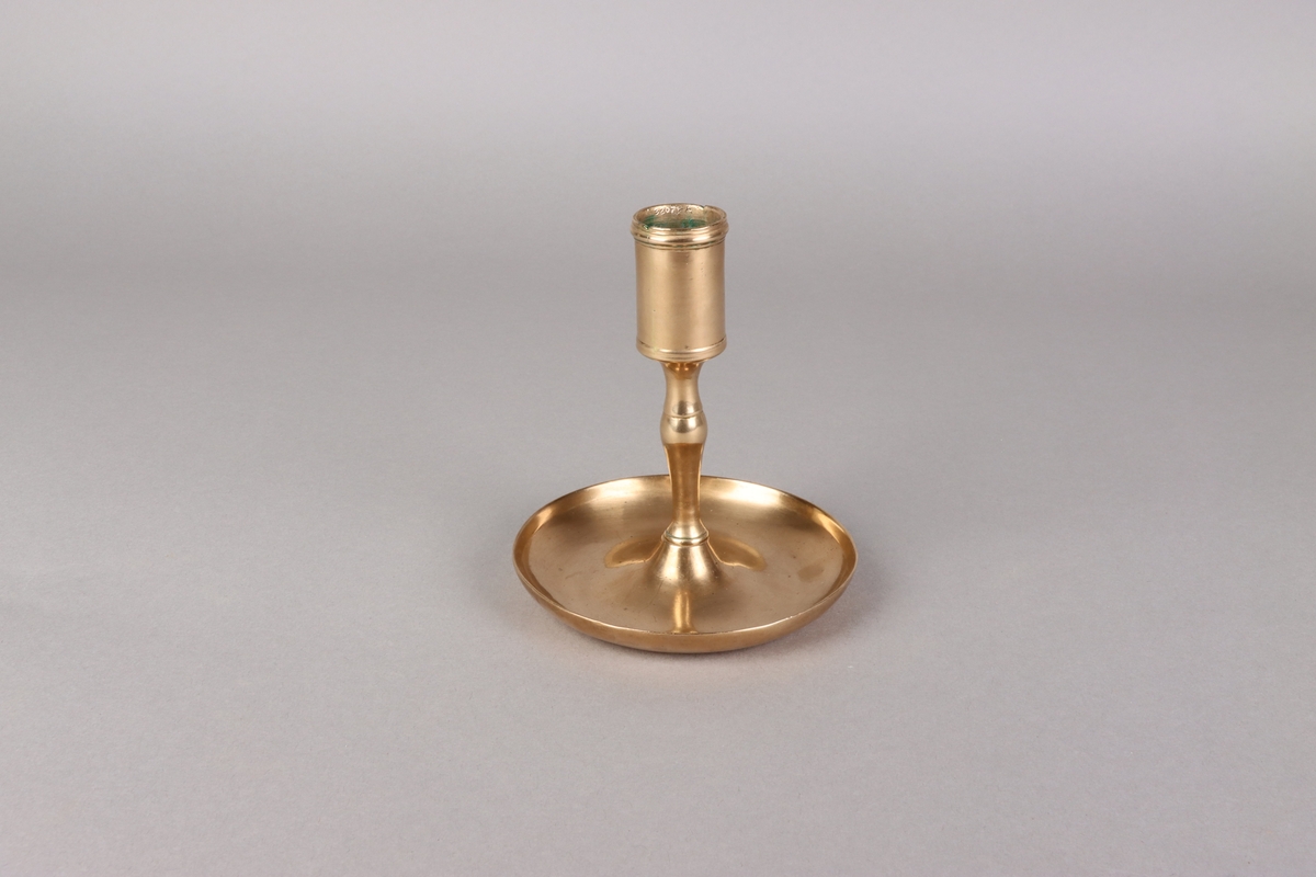 Candlestick, cast brass with baluster steam attached to circle saucer shaped base.