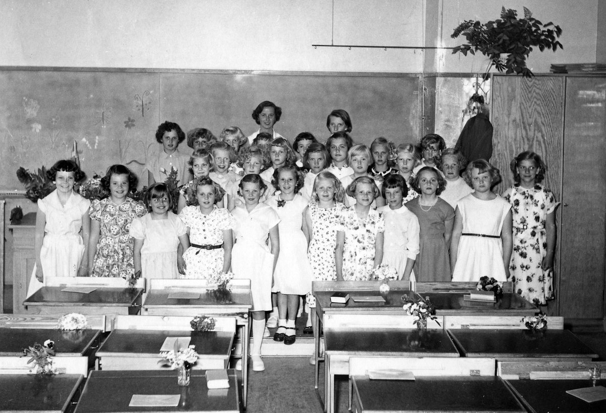 Ett tjugotal flickor fotade vid katedern i ett klassrum. Troligen i samband med en skolavslutning.