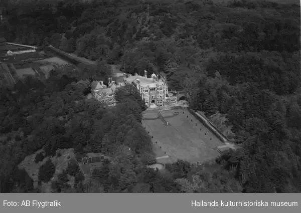 Flygbild över Tjolöholms slott sett från sydväst, omgivet av trädgård, park och skog. Fasaden är vänd mot havet.