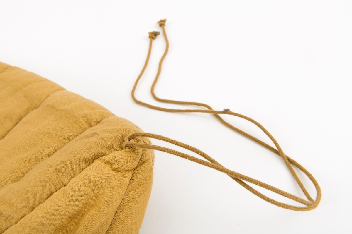 Vattert sovepose med bomullstrekk. Soveposen har en gul-grønn farge. Det er en beige glidelåsåpning i soveposen øvre del. Hodeåpningen er rund i formen, og det er en tynn kant som omslutter hodeåpningen. Hodeåpningen har en omkrets på 13 cm. 
Det festet to snorer på begge ytterkantene av fotenden. Disse snorene er til å knyte sammen den sammenrullede posen for frakt og oppbevaring.

Det er en løs lapp tilhørende soveposen "Medsend vennligst denne kontrollseddel ved eventuell reklamasjon. På baksiden står det Syerske:, Kontroll: . Denne lappen tyder på at gjenstanden er norskprodusert.