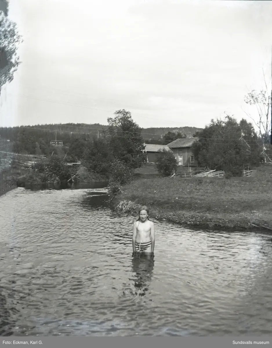 En oidentifierad flicka som badar i Kvarnån i Häre, Indal. Huset i bakgrunden är före detta garveriet på Eckmans gård i Häre. Ur Karl Eckmans samling.
