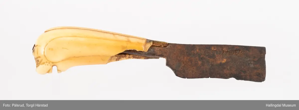Kniv med etui. 
Etuiet er laget av mørkebrunt lær og ullstoff i grønt, rødt, gult og blått. Den er en tilnærmet rektangulær form som er avrundet i bunn og lokk. Er sydd sammen av to stykker med en ytterside og en innerside. Yttersiden er av mørkebrunt lær med påsydd lærkant. Den bredeste delen kan brettes over som lokk og har en utskjært hjerte- og en utskjært tulipanform. Lokket har på innsiden en lærreim som feste. Begge formene er kantet med lyse sting og foret med rødt ullstoff. 
På innsiden er etuiet foret med grønt ullstoff der de lyse stingene fra formene på lokket er synlig. kniven oppbevares i en av fire lommer som er kantet med grønt, gult, rødt og blått ullstoff. Selve yttersiden av etuiet/eller knivsliren er av mørkebrunt lær, kantet med samme lærkant som yttersiden og lokk, og er dekorert med linjer på sidene. Den er også dekorert med en påsydd lærlomme som er foret med rødt ullstoff som synes på kantene. Sydd med lyse sting og er preget med med et kryss og en V. 

Kniven har et skaft med et utskåret dyrehode (hvalross) og et laget av en hvalrosstann. Noe skadd. Knivbladet er festet gjennom hele lengden av skaftet, er rustent og har avbrekte deler på knivbladet. Knivblad stemplet med P. C./eller O. Westlander.