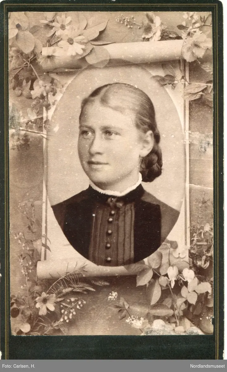 Portrett av ung kvinne gjengitt på en papirull som er omkranset av blomster og bladverk. Minnebilde? Mathilde Røtnes.