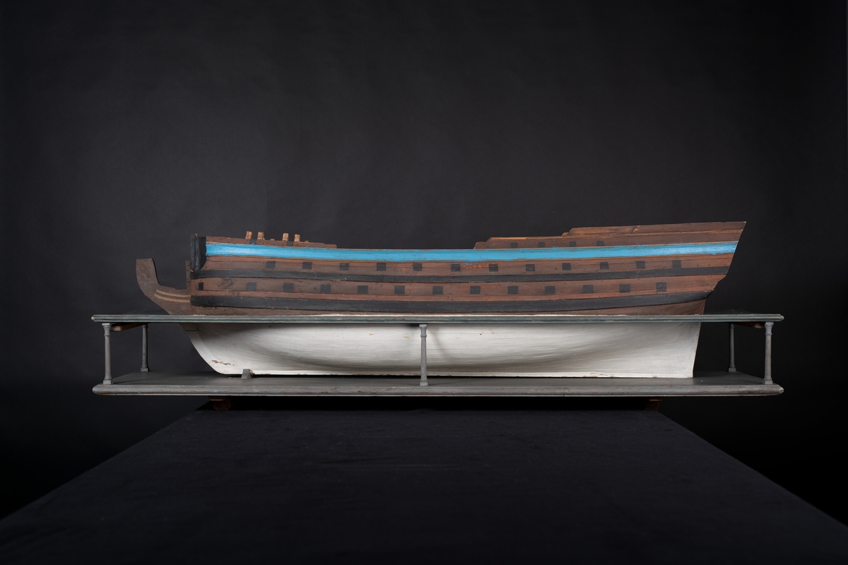 Fartygsmodell 60-kanonskeppet Prins Carl, skrovmodell. Bordläggningen limmad på gavlar, utan inredning, galjon och akterspegel. Modellen är brunmålad upptill med blå rand och svarta kanonportar. Under vattenlinjen vitmålad.