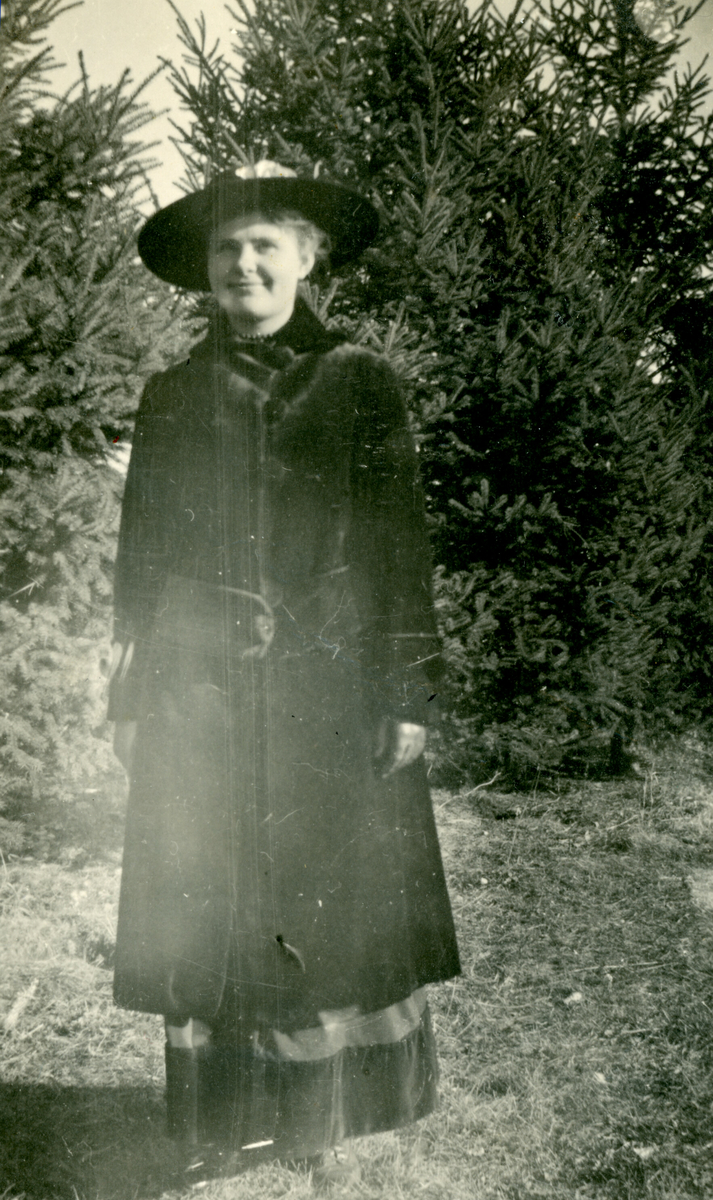 Ukjent kvinne i Amerika fotografert ute i naturen m. kåpe og hatt.