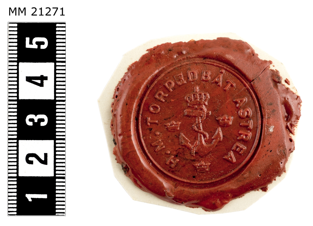 Sigillavtryck av rött lack på papper. I mitten krönt stockankare omgivet av tre kronor. Längs kanten text: "H.M. torpedbåt Astrea".