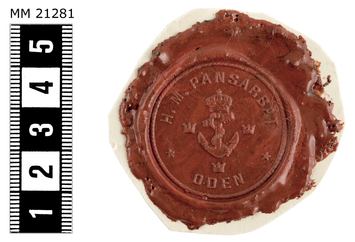 Sigillavtryck av rött lack på papper. I mitten krönt stockankare omgivet av tre kronor. Längs kanten text: "H.M. Pansarbåt Oden".