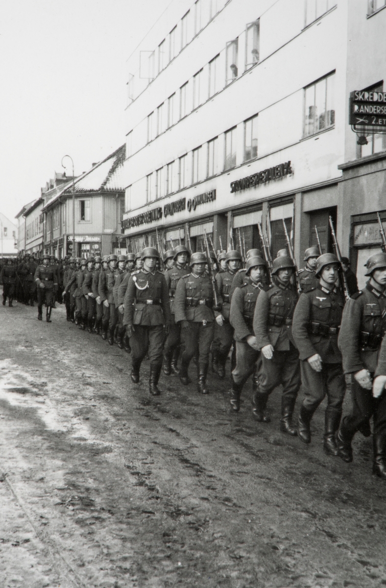 Tyske soldater marsjerer gjennom Torggata 41-43, Hamar. Okkupasjon, 2. verdenskrig