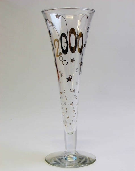 Konformat champagneglas i vitt glas med guldig dekor i form av stjärnor och prickar samt årtalet 2000. Rund fot. Tillverkat till millennieskiftet 1900-2000.