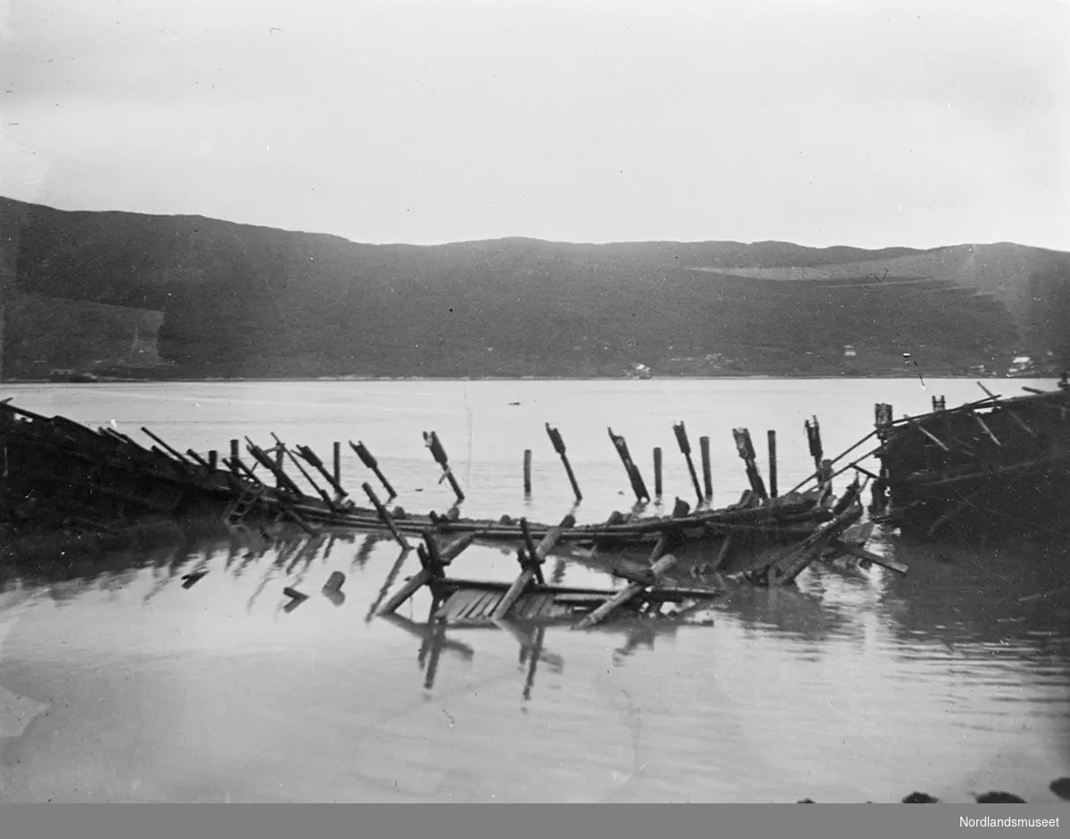 LKABs kullkai etter stormen i 1901. Til venstre ses kaien med påler og stokker som støtter opp mot kaien. Til høyre ses havna med båter. I bakgrunnen en del av Fagernesfjellet og Fagernes. En del av Ankenesfjellet forsvinner innover mot Beisfjord.