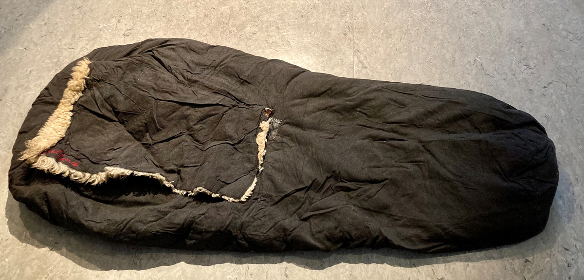 Mørk grå sovepose i stoff, foret med saueskinn.