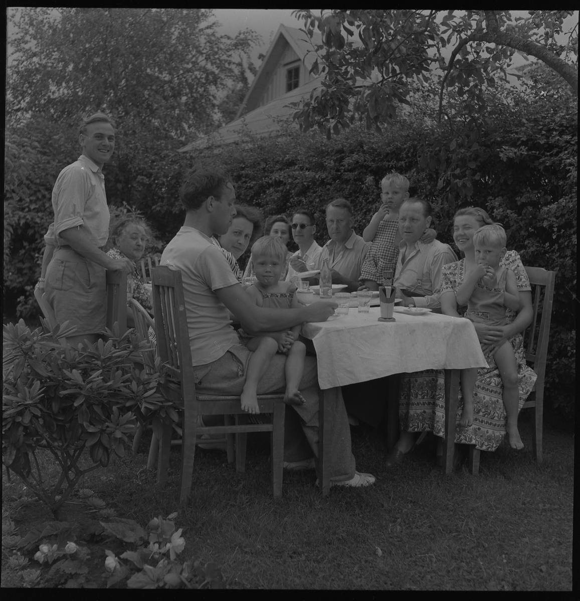 Kalas i trädgård. På bordet står en burk från Lidköpings konfektyr AB. 24 juli 1950