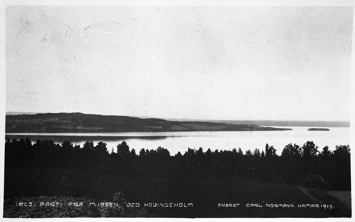 Postkort fra 1919 med påskrift "PARTI FRA MJØSEN VED HOVINDSHOLM". Fotografens standplass har tydligvis vært på Toten-sida, og med Helgøya og Hovindsholmen midt imot.