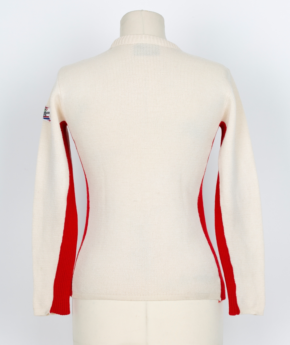 Genser. OL genser fra Insbruck 1976. Lange ermer. Rund hals. Hvit, rød og blå i felter og stripet.
Merke med 5 olympiske ringer og Insbruck 1976 påsydd ermet.