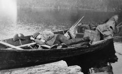 Liggende tømmerfløter i robåt med neverkont, ryggsekker, mat