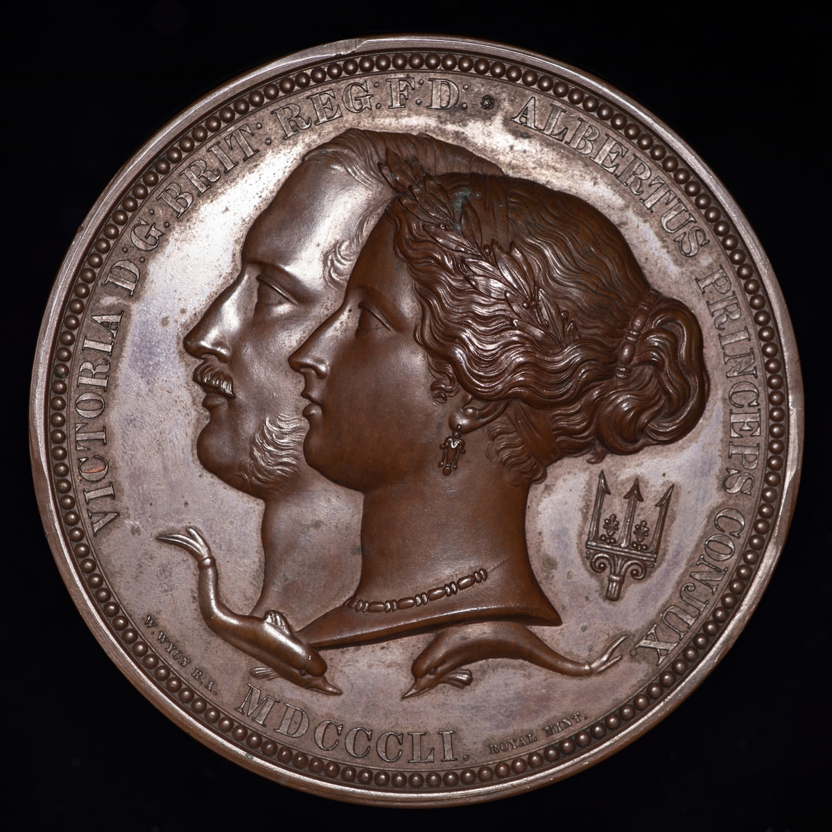 Bronsemedalje fra 1851. På adversen dronning Victoria og prins Albert i profil mot venstre. På reversen er hovedmotivet at en kvinnelig guddom(?) en laurbærkrans til en annen kvinne.