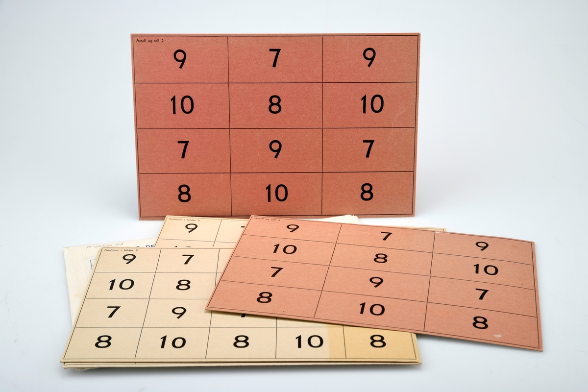 Fem identiske spilleplater med tema "Antall og tall 2. Tallene 7-10" i konvolutt. Platene har påtrykt 4 rekker med tallene 7 til 10 plassert på ulike ruter. Det er ialt 20 ruter. Tre av platene er hvit med svarte tall mens to av platene  er rosa med svarte tall. Baksiden av platene er hvit med firkanter/trekanter i turkis på tre av platene og i gult på to av platene. Platene ligger i en konvolutt med blå påskrift. På konvolutten er det tegning av fire elever som spiller spillet samt informasjon Palins regnespill generelt. På baksiden er det oversikt over ulike typer spill, spilltilbehør og vanskelighetsgrad.