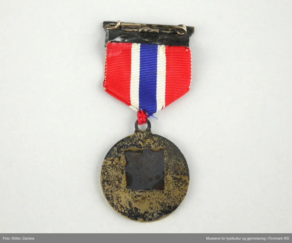 Medaljen er rund og i gull valør. På forsiden er motivet en kulestøter.
Medaljen er opphengt i et rødt bånd med en midtstripe i hvitt, blått og hvitt. Båndet er utstyrt med en metallklemme øverst der øvelsen er gravert i. Klemmen har en brosjenål på bakside.