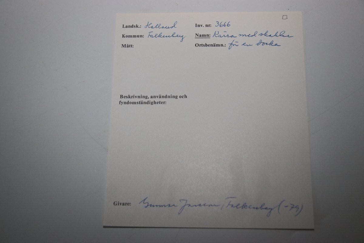Nr 3666. Dockkärra. Halland, Falkenberg. Träkärra för docka med skaklar och röda järnbeslagda hjul. Förvärvat från Gunnar Jansson, Falkenberg (1979).