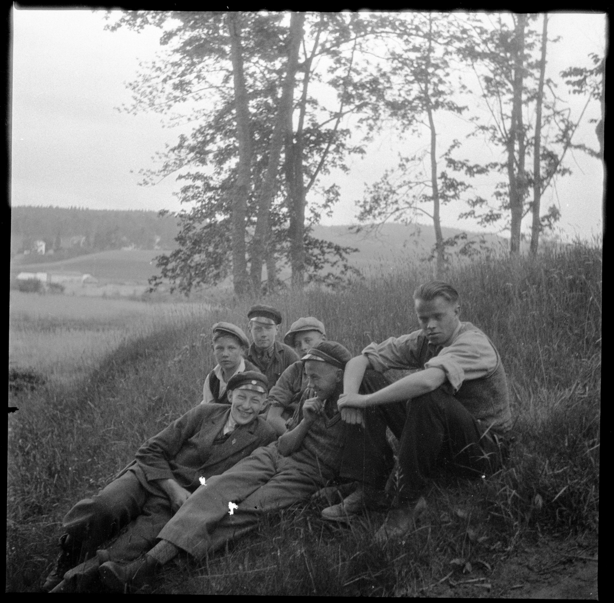 Fil. stud. Anders Lindahl till höger, tillsammans med fem skolpojkar vid Rumlaborg i Huskvarna. Fotot är taget i samband med arkeologiska undersökningar vid borgen sommaren 1935. Anders Lindahl var projektledaren Georg Sahlströms närmaste man vid undersökningen.