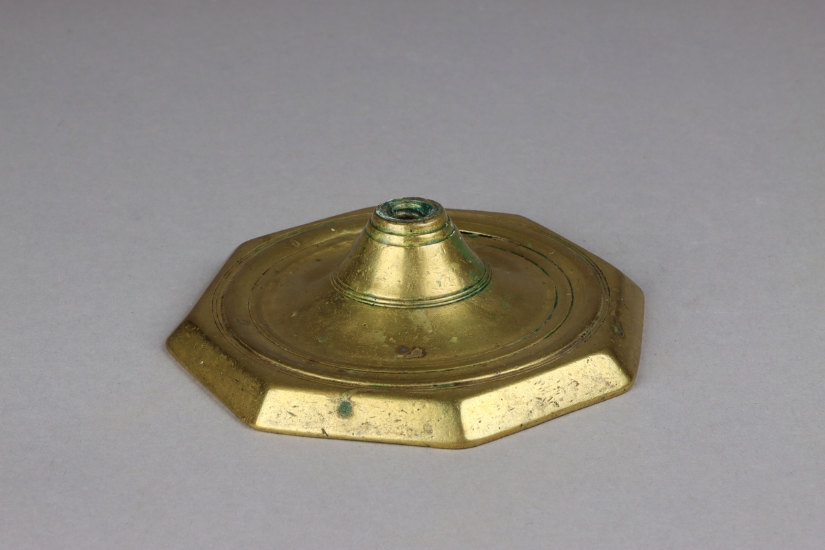 Foot, part of a brass candlestick. Octagonal with sunken centre and conical base for the steam.