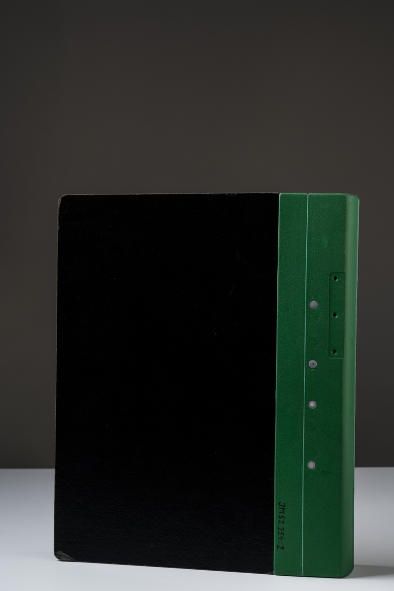 Pärm med grön plastrygg med svarta relieftryckta pappsidor. Pärmlåset är av metall, öppningsanordningen är av svart plast. Ryggen viks utåt som ett gångjärn när man öppnar pärmen. Patent 4 352 582 i USA och i Sverige 80004245-0.