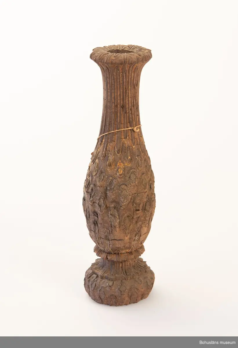 Ormbunksstam formad som en vas, men med hål genom stammen. Stammen ornamenterad.