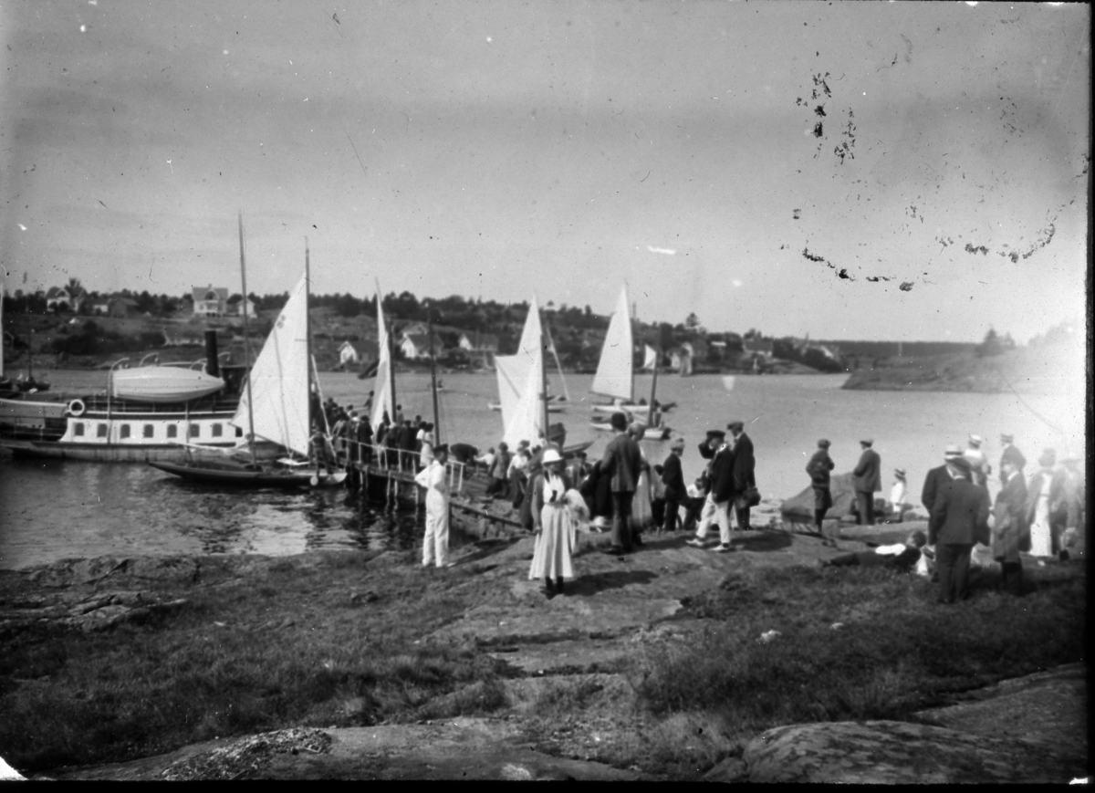 Landsregatta i Kragerø. 1914. Folk på svaberg, seilbåter og dampskip.
Tåtøy mot byen i bakgrunn?