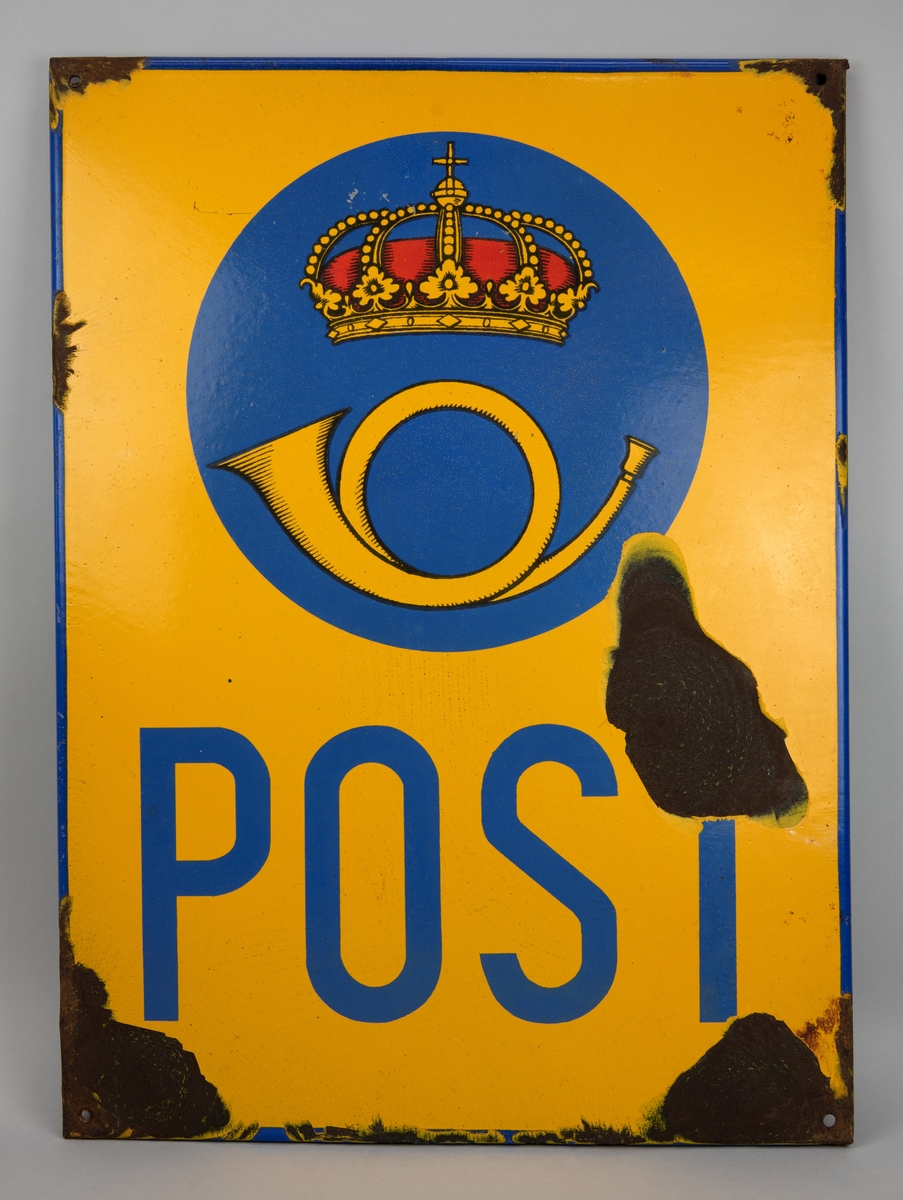 Rektangulär reklamskylt av emaljerad plåt. Gul botten med "POST" i blått samt postens emblem. 
Fyra hål i vardera hörn för uppsättning.