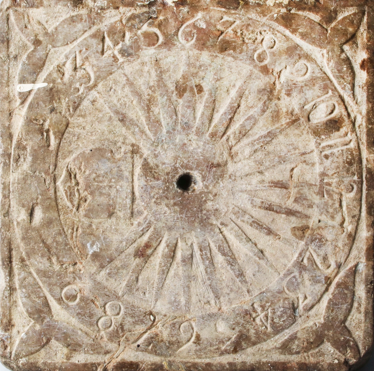 Sten, kvadratisk. Rund sifferkrans med arabiska siffror. Hål för visare i mitten (saknas nu). Från hålet utgår solstrålar. Under hålet vapensköld. I svicklarna treflikiga blad. Troligen tillverkad på 1700-talet.

Funktion: Tidvisare