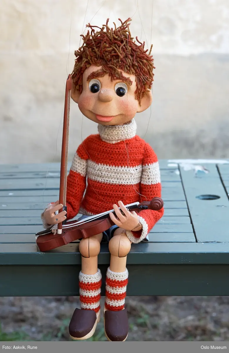 Marionette. Liten gutt med brunt krøllette hår og rød/hvit genser og sokker.