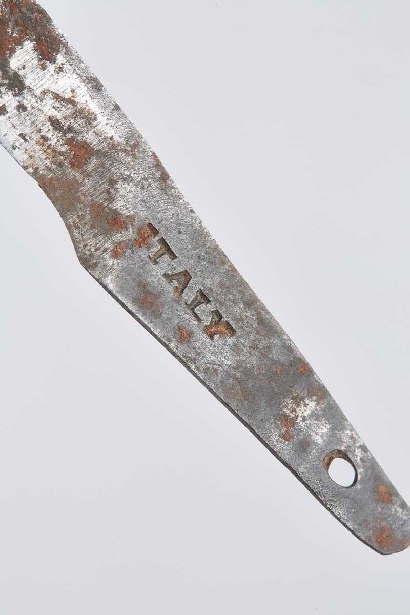 Barberskrinet (a) er umalt, skyvelokk rikt utskåret på sider og lokk. Barberkniv (b) med hornskaft og stålblad, bladet kan foldes inn i skaftet. Reserveblad (c).