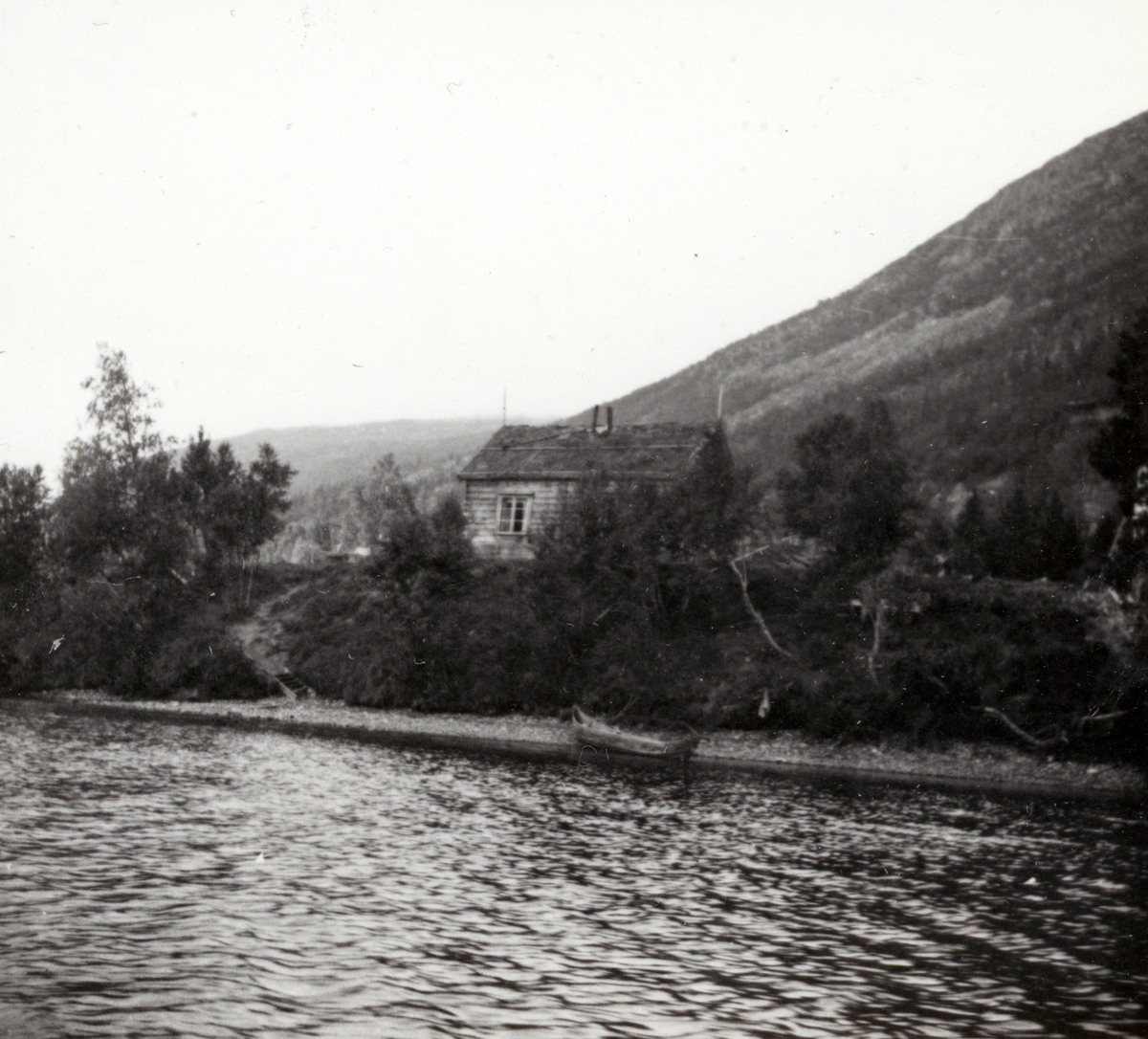 Hus i Bilto og elvebåt fotografert fra Reisaelva (1946-1950).