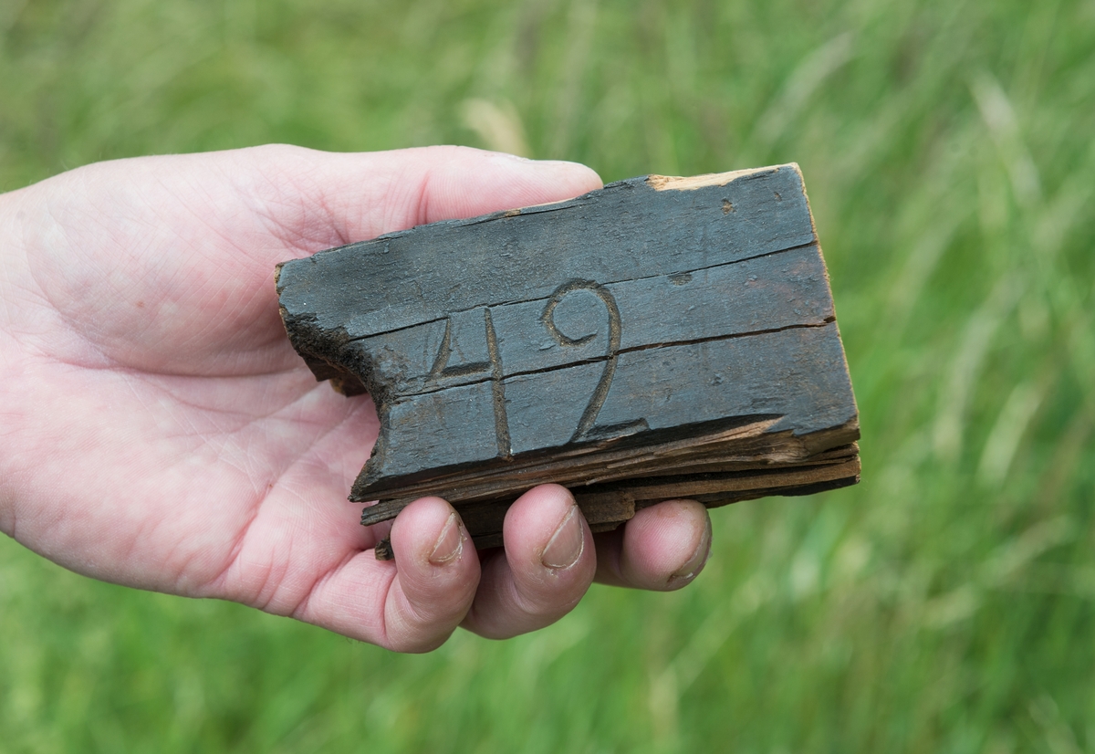 Båtdel. En bit trä med inskriptionen "42" från en baltisk flyktingbåt som kom till Sverige under andra världskriget. 
