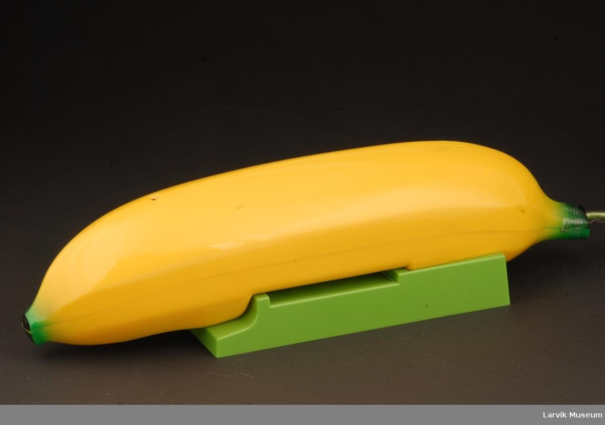 Bildet viser en gjenstand formet som en gul banan. Den ligger på en grønn plastdings. (Foto/Photo)