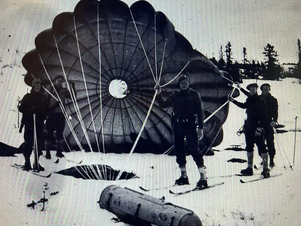 fallskjerm på bakken og menn på ski - under krigen