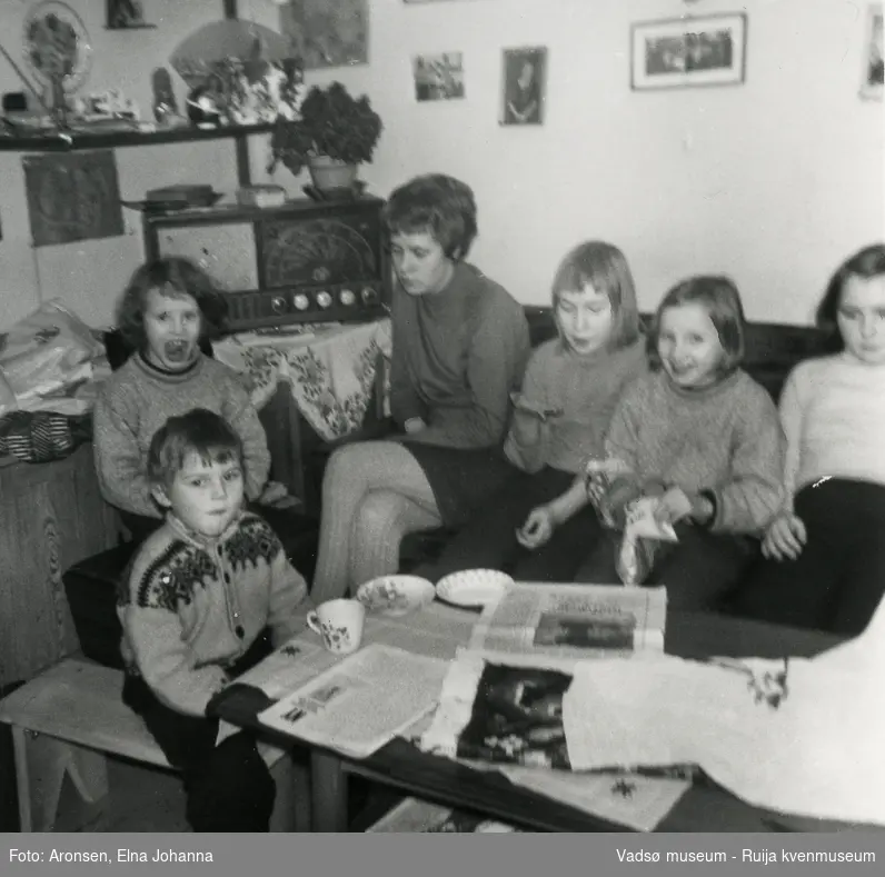 Barn og voksne har benket seg i sofaen foran radioen og hører på lørdagsbarnetimen, ca 1969. Fra venstre foran, Steffen Aronsen, Heidi Søfting, Ragnfrid Aronsen, Liv-Erna Aronsen, Aud Lillian Søfting og Joronn Aronsen.