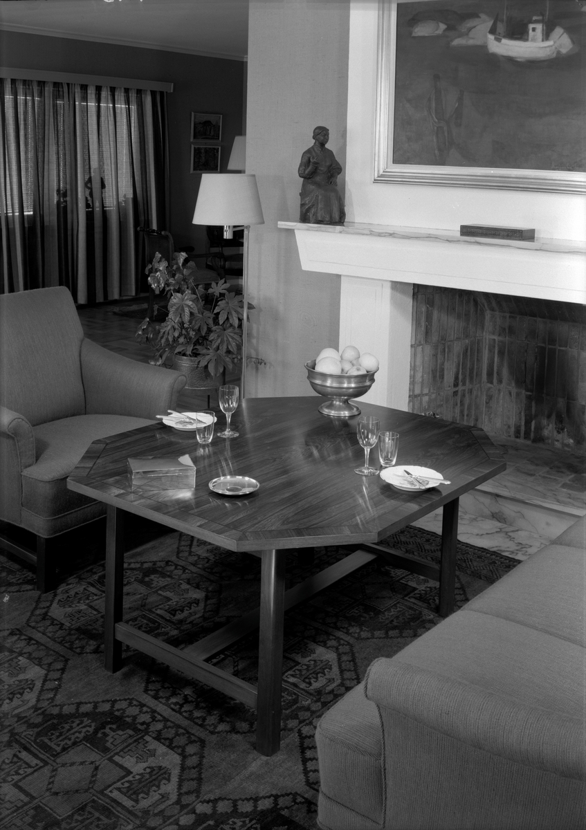 Detaljbilde av interiøret i en stue fra slutten av 1950-tallet. Et kaffebord er dekket foran peisen.