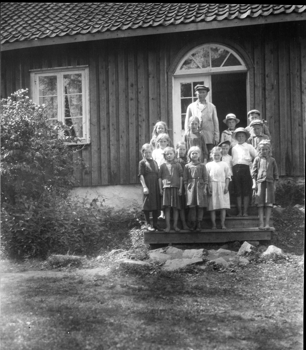 Fjorten barn og en stor gutt arbeidsgutt foran inngangsdør/portal på Langøy hovedgård.
