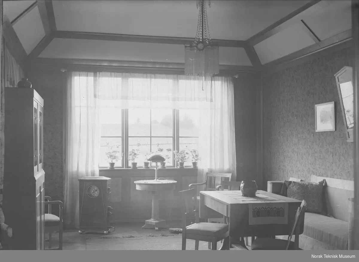 Stuebord med elektrisk lampe, spisebord og sofa; stueinteriør fra mønsterbruket på NEBB's jubileumsutstilling i 1914