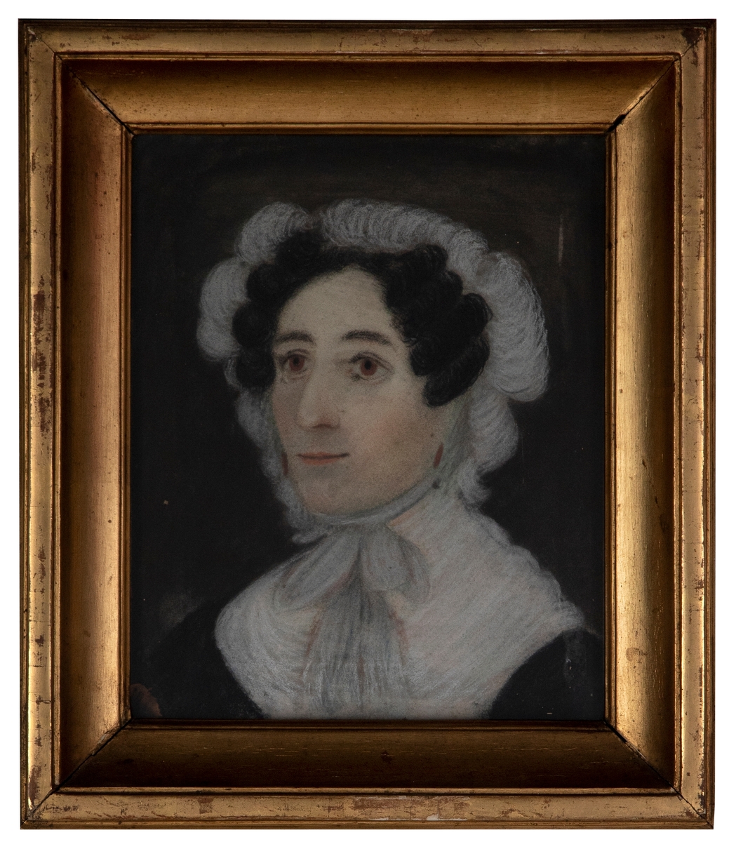 Portrett av en kvinne med mørkt oppsatt hår og brune øyne. Kvinnen er iført en innendørs hodekappe i hvit med knyting i halsen og en hvit krage over en svart kjole.