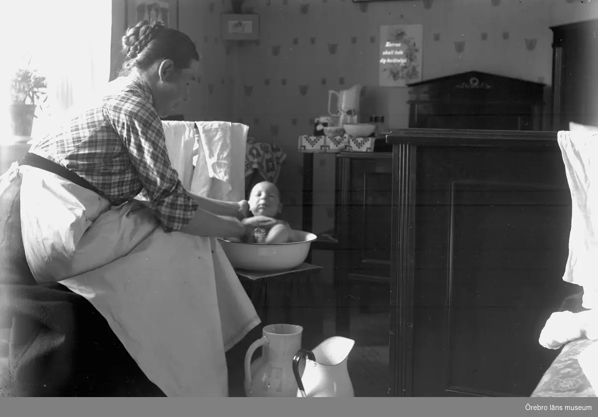 Kvinna tvättar en baby.
Anna Gustavsson (dotter till Edvard Thermaenius) med sonen Gunnar.