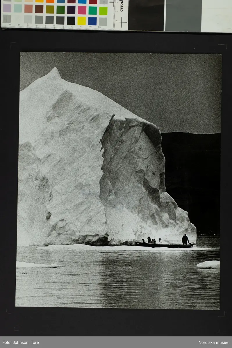 Människor i en båt på vattnet framför ett isberg. Mellan Baffin Island, Canada och Grönland, skolskjuts.