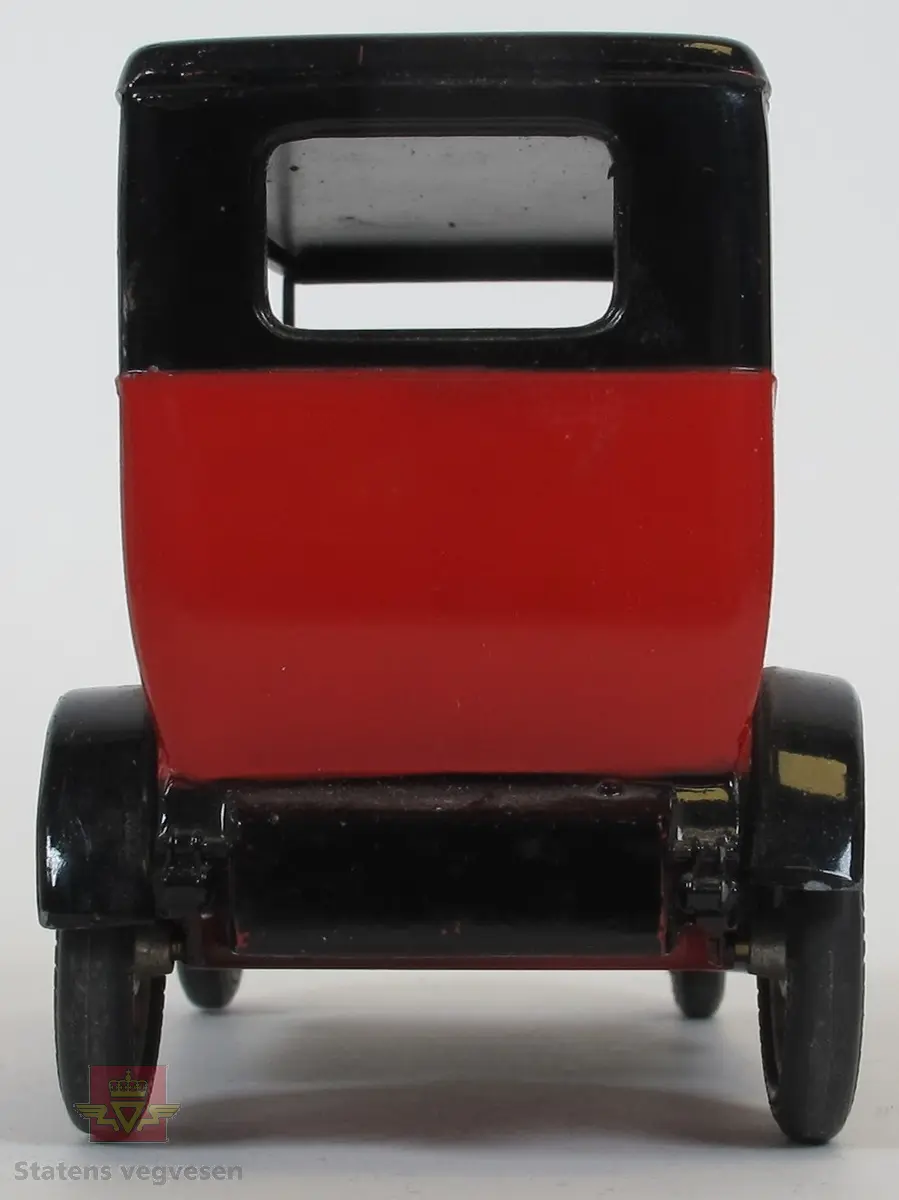 Rød modellbil med svart tak og hjulbuer. Festet til reservehjulet og selve hjulet mangler.