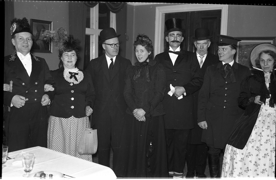 En grupp kvinnor och män klädda likt tidigt 1900-tal, troligen på Ribbagården i Gränna. Från vänster Tage och Maj Grennfelt, Percy och Birgit Heldebrandt, okänd, okänd, Hans Roman samt Dagmar Petri.