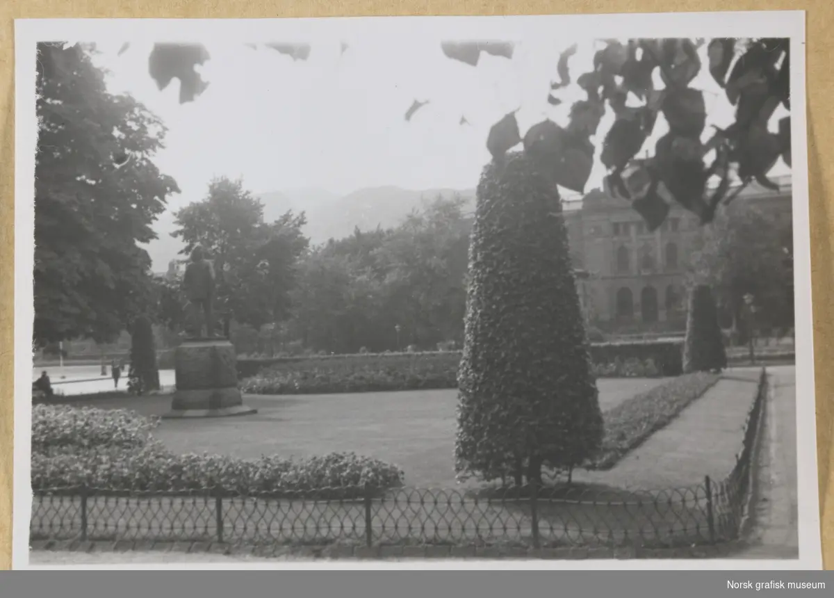 Utendørsmotiv, fra Byparken i Bergen. Til venstre ser vi statuen av Edvard Grieg, i bakgrunnen til høyre skimtes musikkpaviljongen og bygningen bak den. Fotografert i forbindelse med Vestlandsk Trykkerstevne i Bergen, 1946.