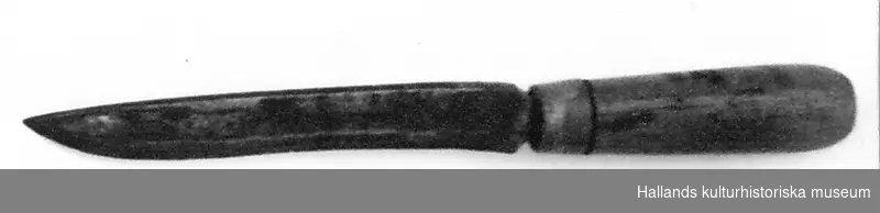 Kniv av järn med svarvat handtag av ask. Med ring av koppar. (1,2 cm) som skoning. Längd 30,5 cm. Bredd (bladets största) 2,7 cm. 