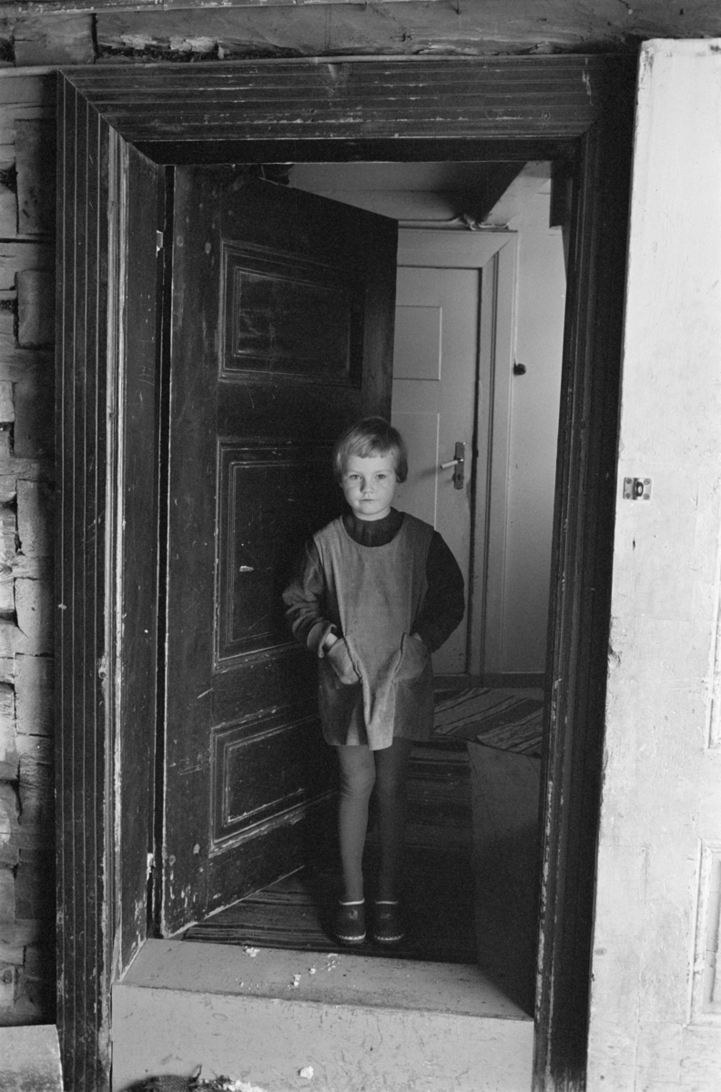 En jente står i en døråpning.