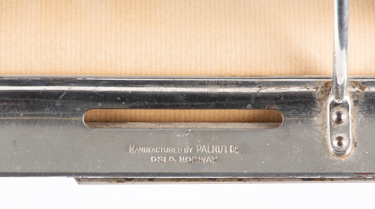 Papirrullstativ i klarlakkert eik og forniklet jern. Stativ til 3 pairruller av ulik bredde. Mrk: Manufactured by Palnut & co - Oslo, Norway/ Patents pending.